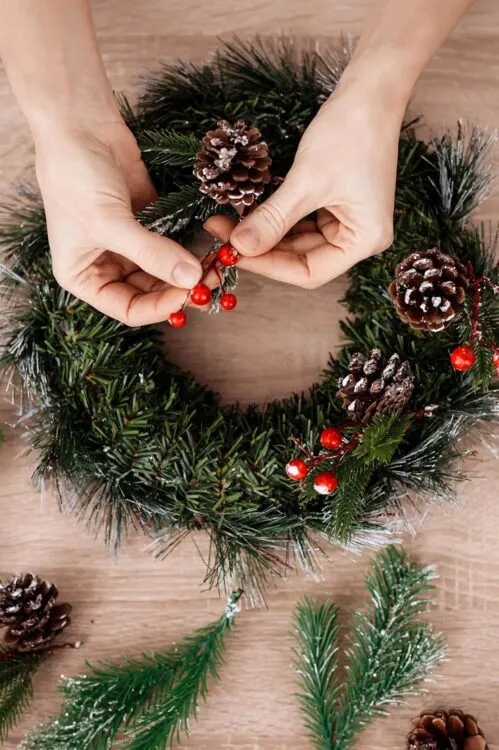 Woman is making jewelry for the Christmas holidays. Girl is engaged in manufacture of wreaths.